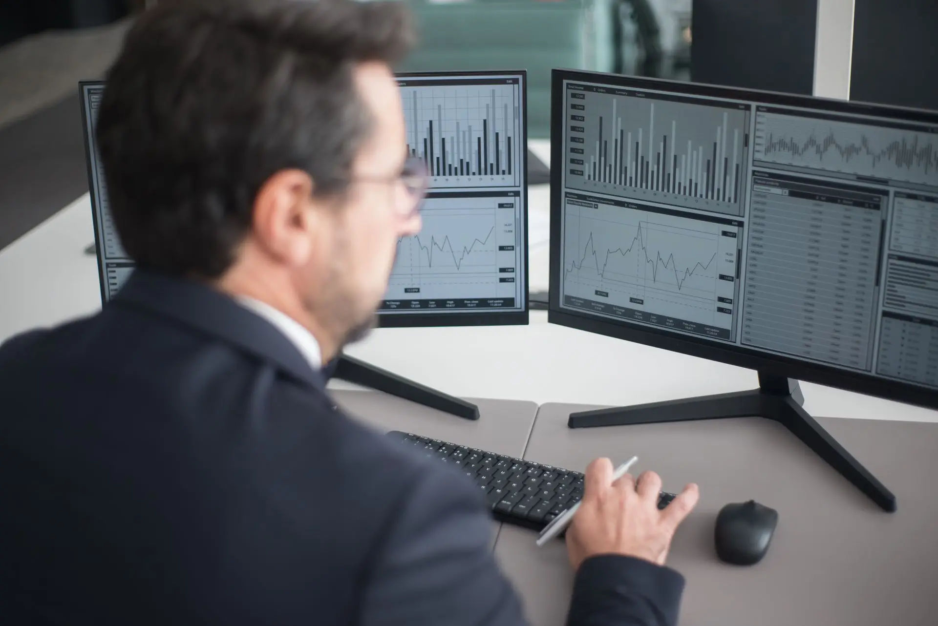 A transport administrator at a desk reviewing shipment dashboards across two monitors.